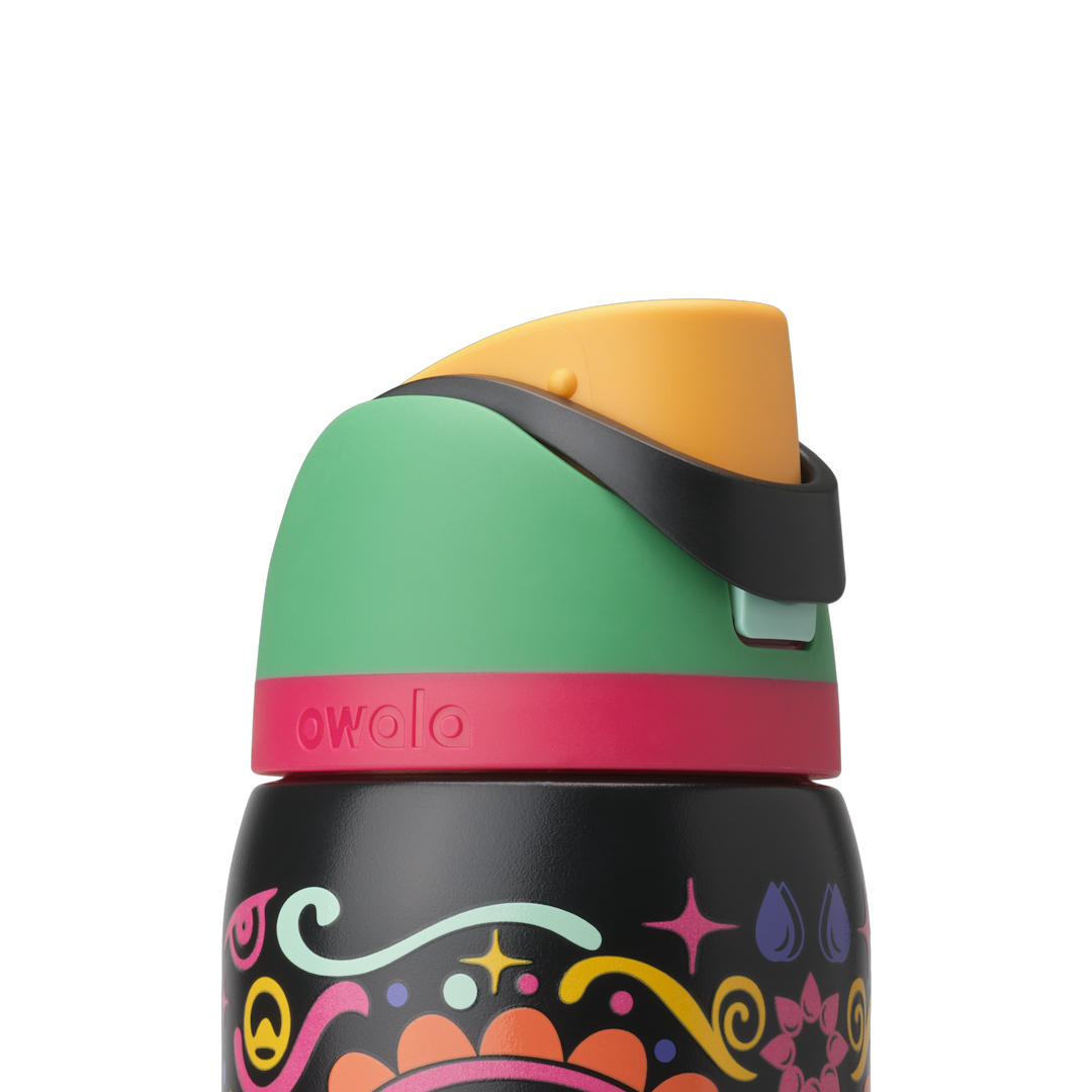 Owala FreeSip Sway 32oz in Sugar Skull, lid detail showing green flip cap, orange push-button, black carry loop, and pink lid accent ring over sugar-skull patterned body; glows in the dark